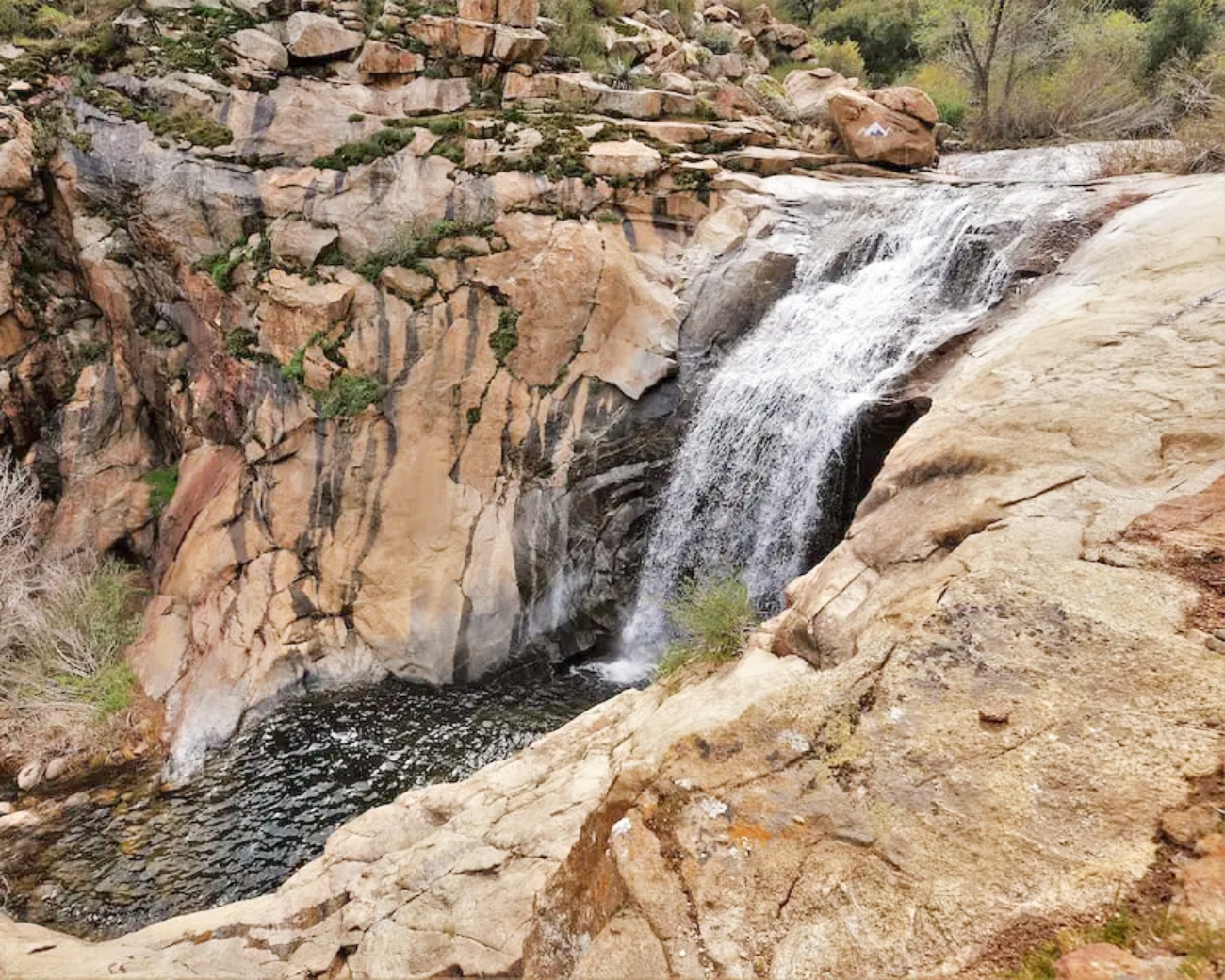 A California woman fell to her death on Thursday after she lost her footing while reaching out to help a teen who had slipped on the ledge of a waterfall, authorities said.